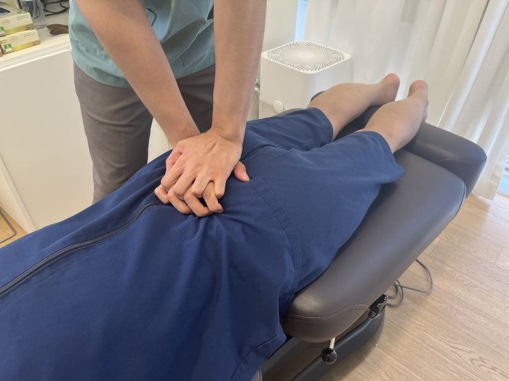 옆으로 누운 환자의 허리를 교정하는 모습
