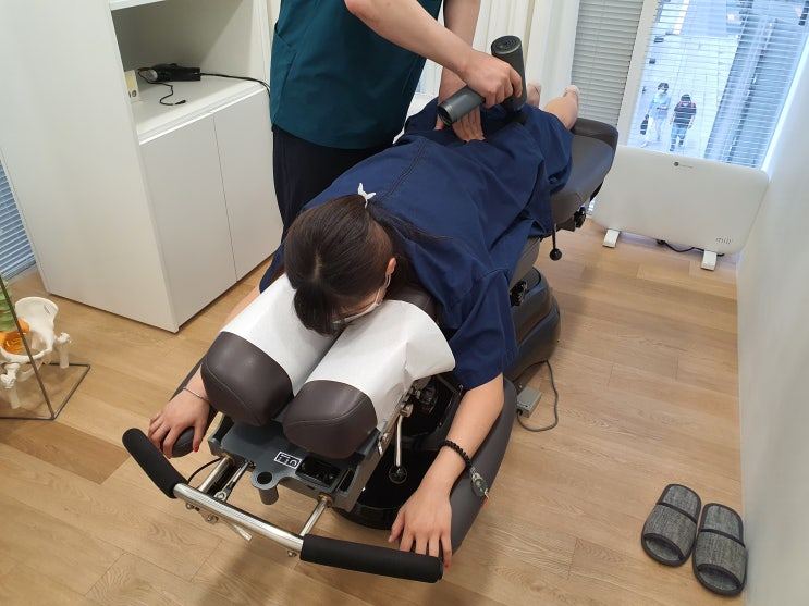 엎드린 환자에게 의료진이 기구로 허리 치료를 하는 사진