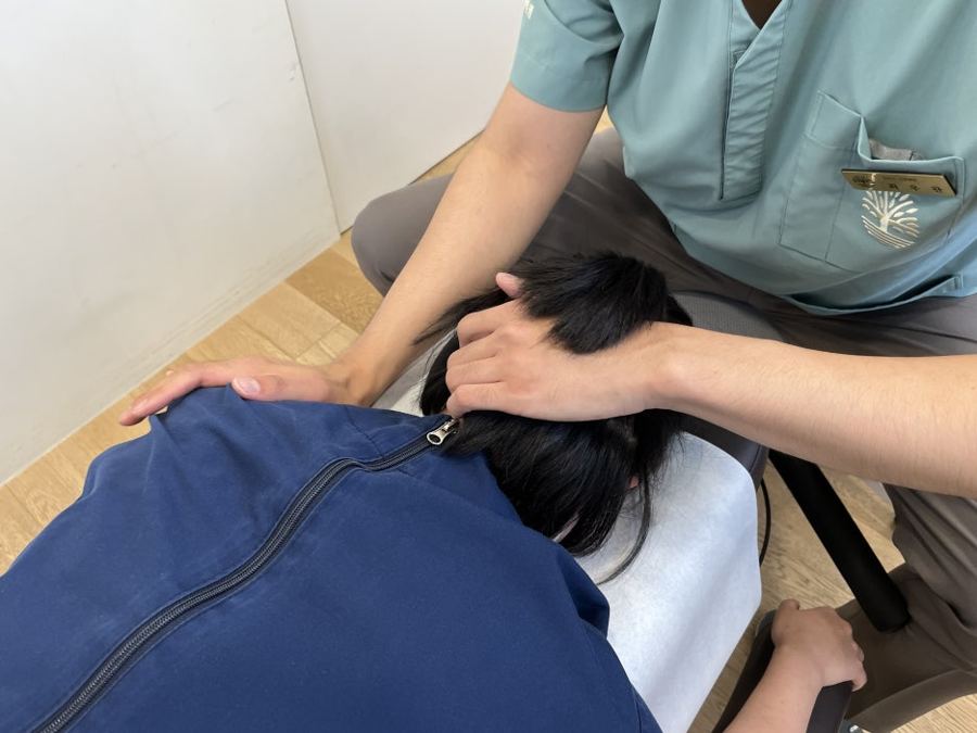엎드린 환자의 목과 어깨를 손으로 치료하는 장면